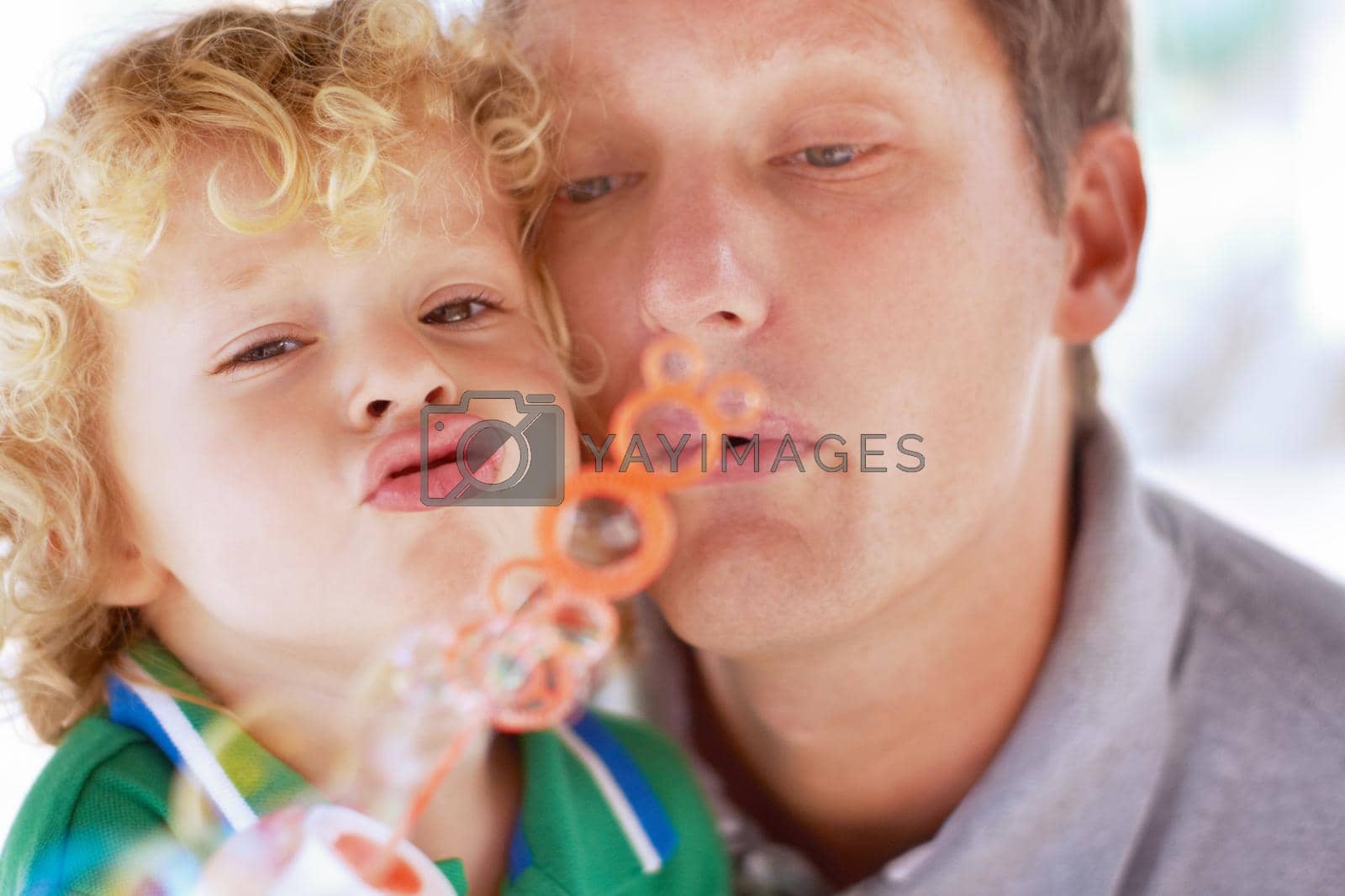 A father and son blowing bubbles together.
