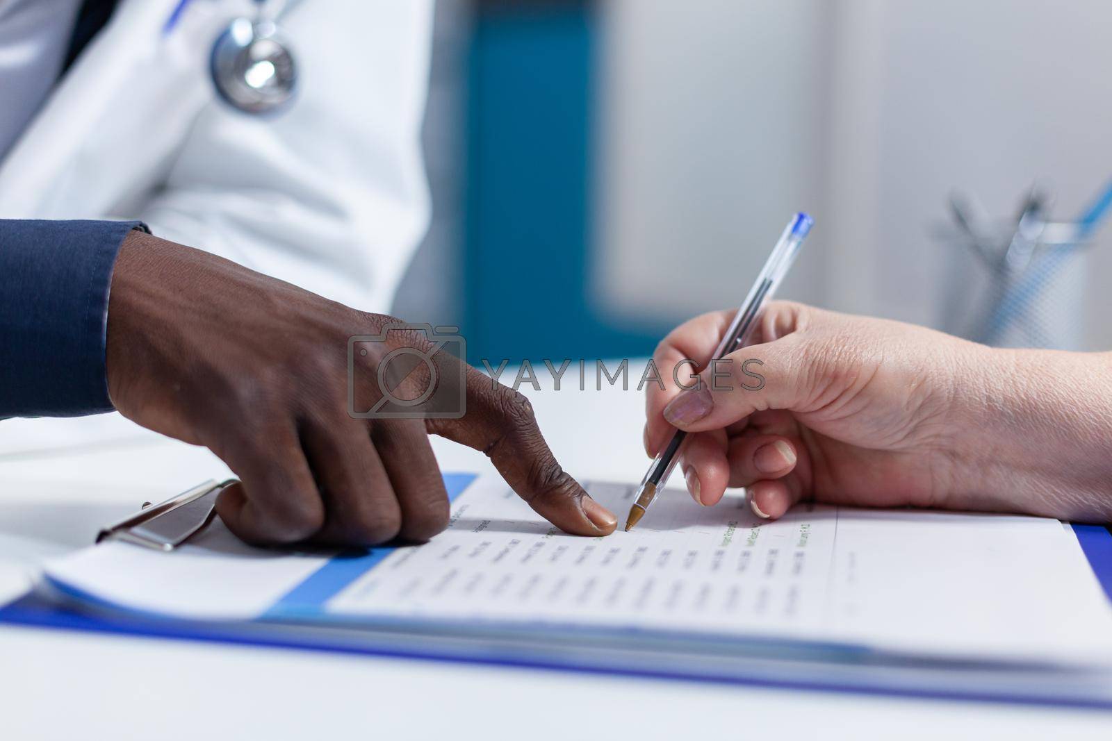 Close up of woman hand signing healthcare coverage policy and prescripted medication. Hospital physician showing woman medical documents, illness history and and healthcare coverage policy