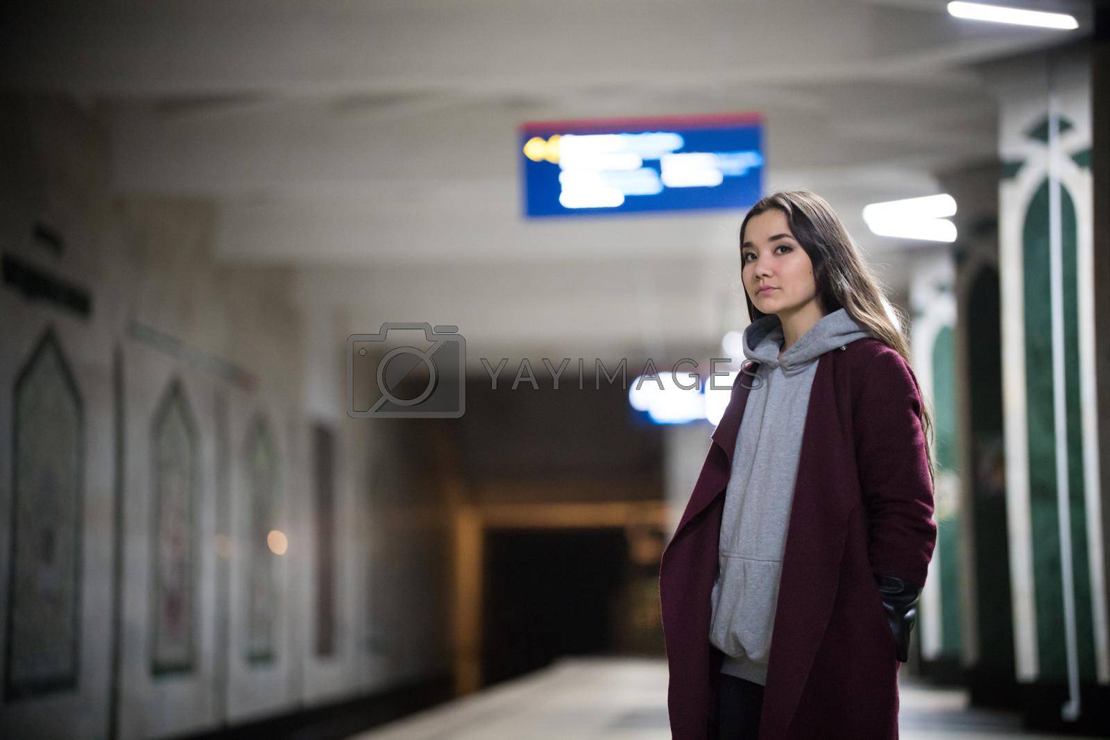 Young pretty woman waiting for the train in subway platform. Night