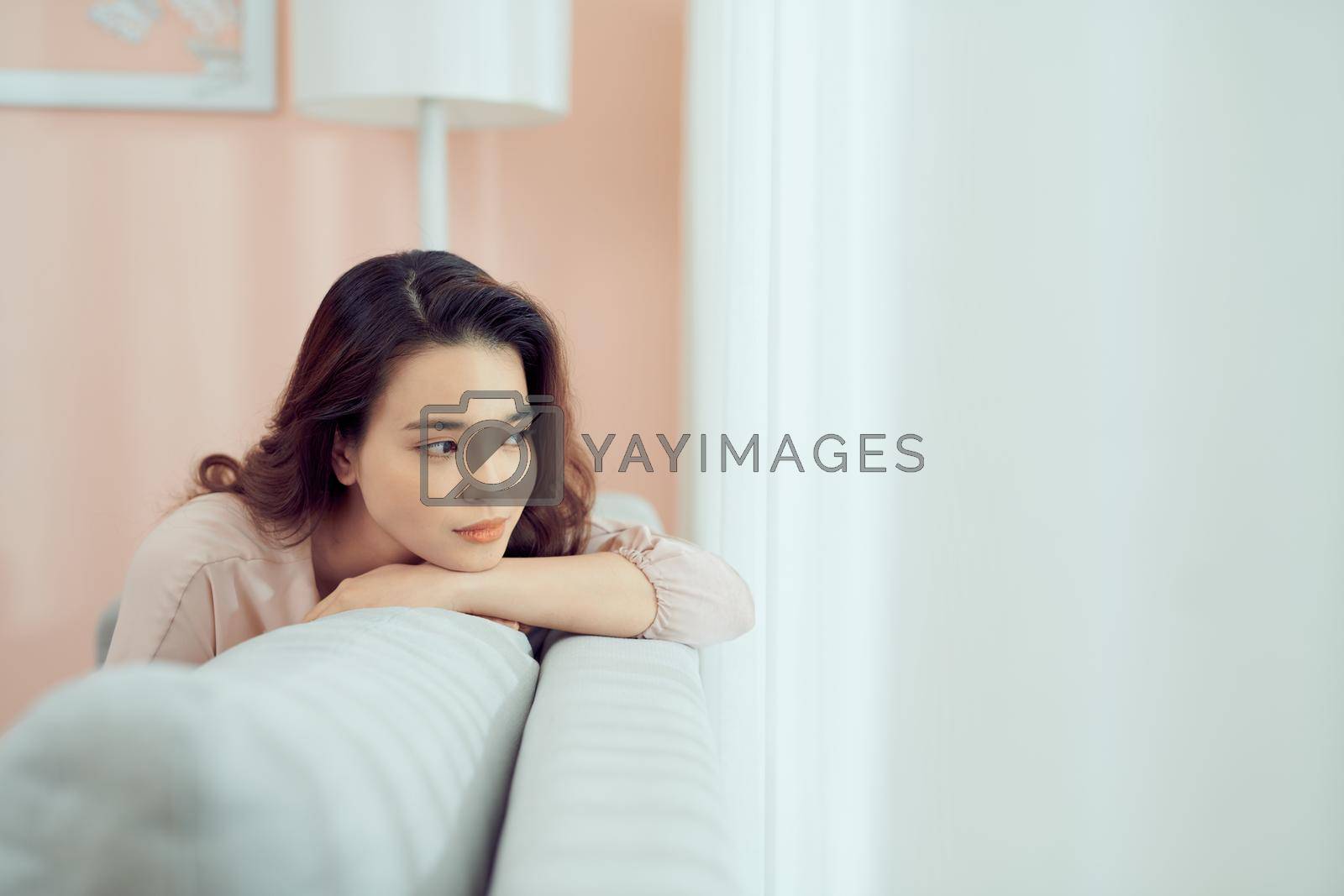 Royalty free image of Sad woman sitting on sofa at home deep in thoughts, thinking about important things by makidotvn