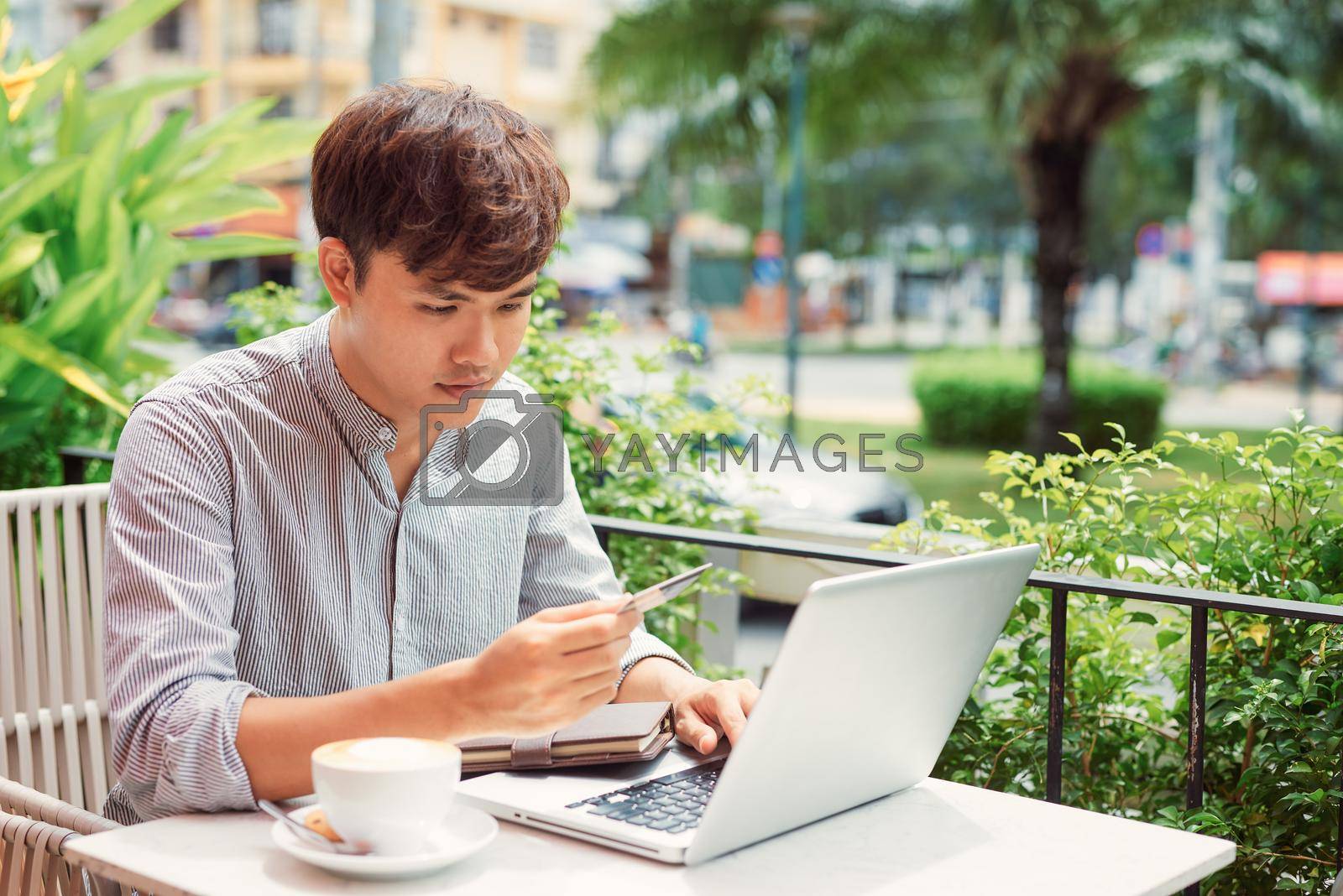 Royalty free image of Relaxed man writing in a laptop in a coffee shop by makidotvn