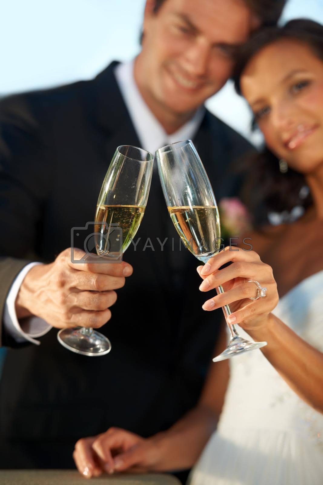 Royalty free image of Heres to us. Cropped view of a young bride and groom standing together and toasting their marriage. by YuriArcurs