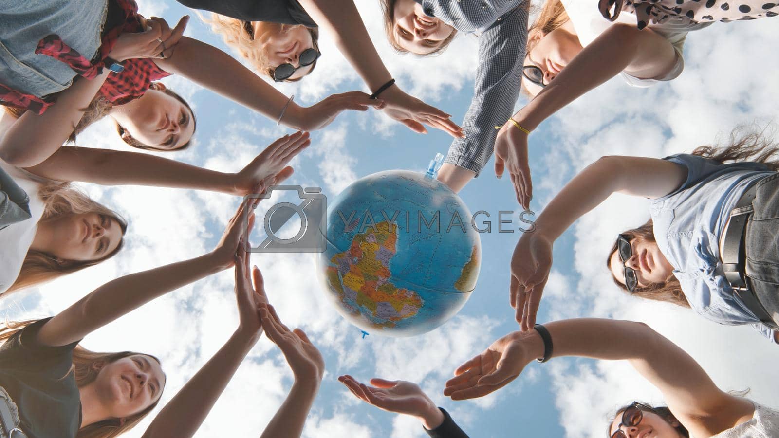 Royalty free image of Earth conservation concept. 11 girls surround the rotating earth globe with their palms hands. by DovidPro