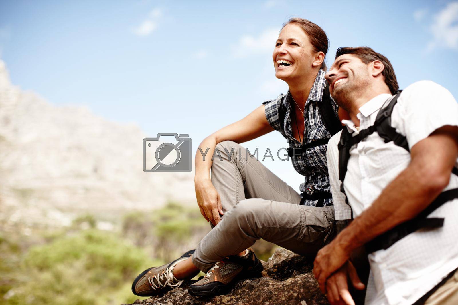 Two hikers laughing and smiling while enjoying a mountain top view.
