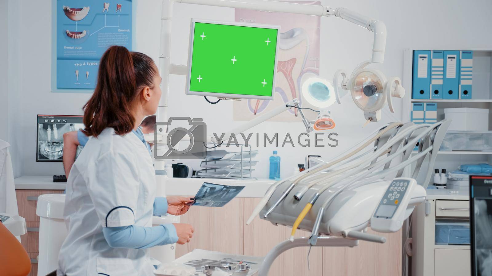 Dentist receiving teeth scan from man while looking at green screen on monitor. Specialist doing oral care examintion with radiography and isolated chroma key in dentistry cabinet