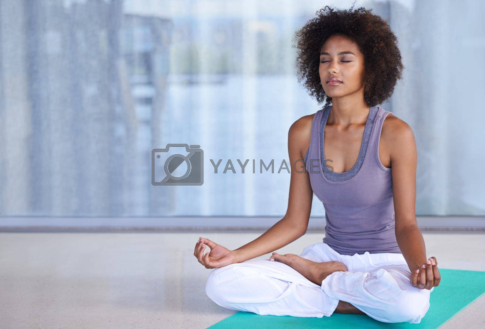 Royalty free image of Finding inner peace. Shot of an attractive young woman meditating on an exercise mat. by YuriArcurs