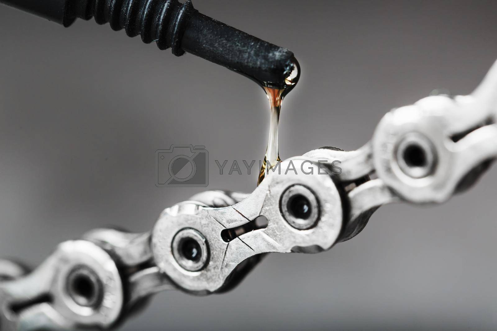 Royalty free image of Lubricating a bicycle chain with a drop of oil close-up on an isolated gray background by AlexGrec