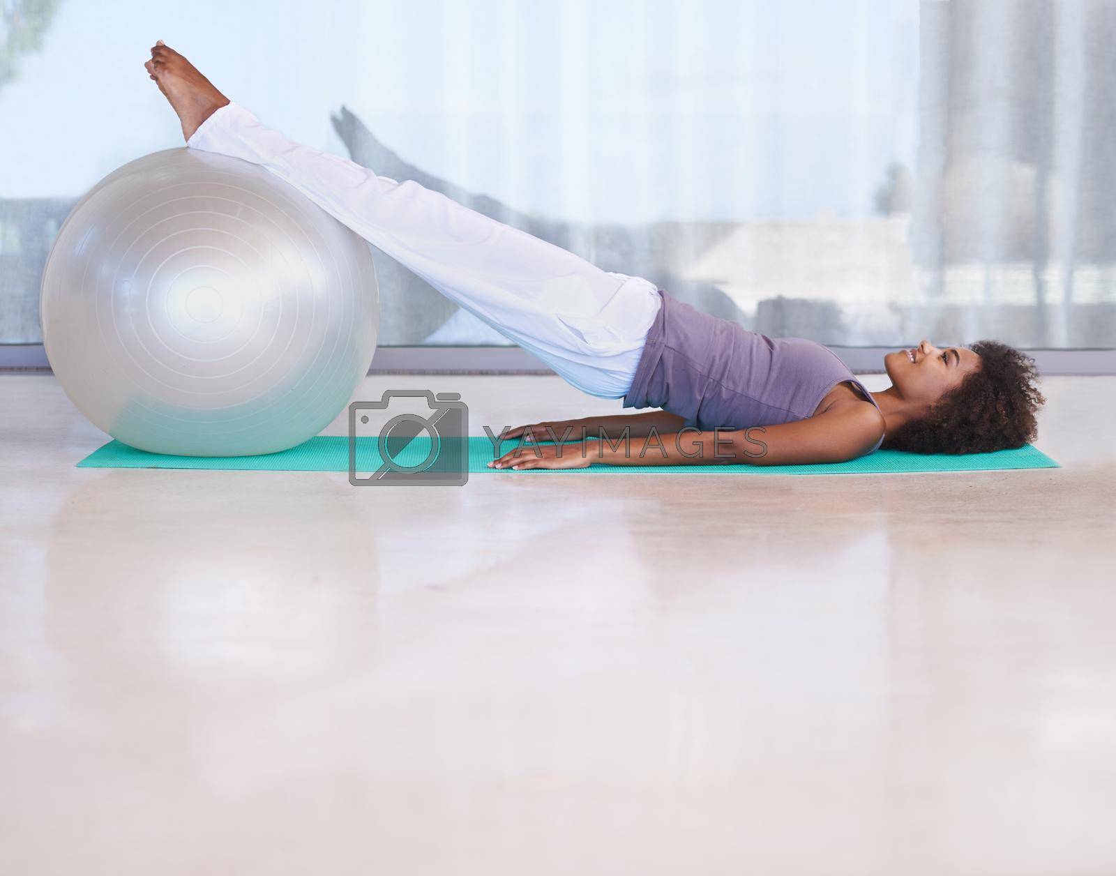 Royalty free image of Strengthening her core. Shot of an attractive young woman doing pilates with an exercise ball. by YuriArcurs
