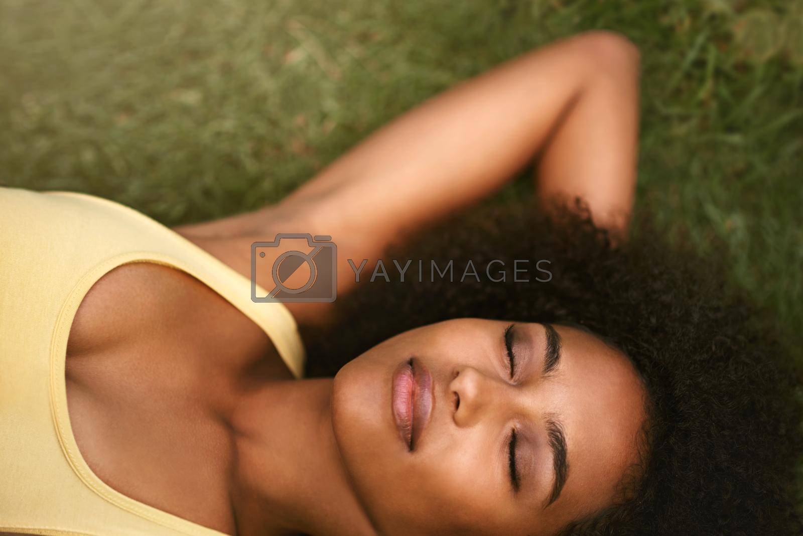 Royalty free image of Absolute bliss.... Shot of a relaxed young woman lying on the grass with her eyes closed. by YuriArcurs