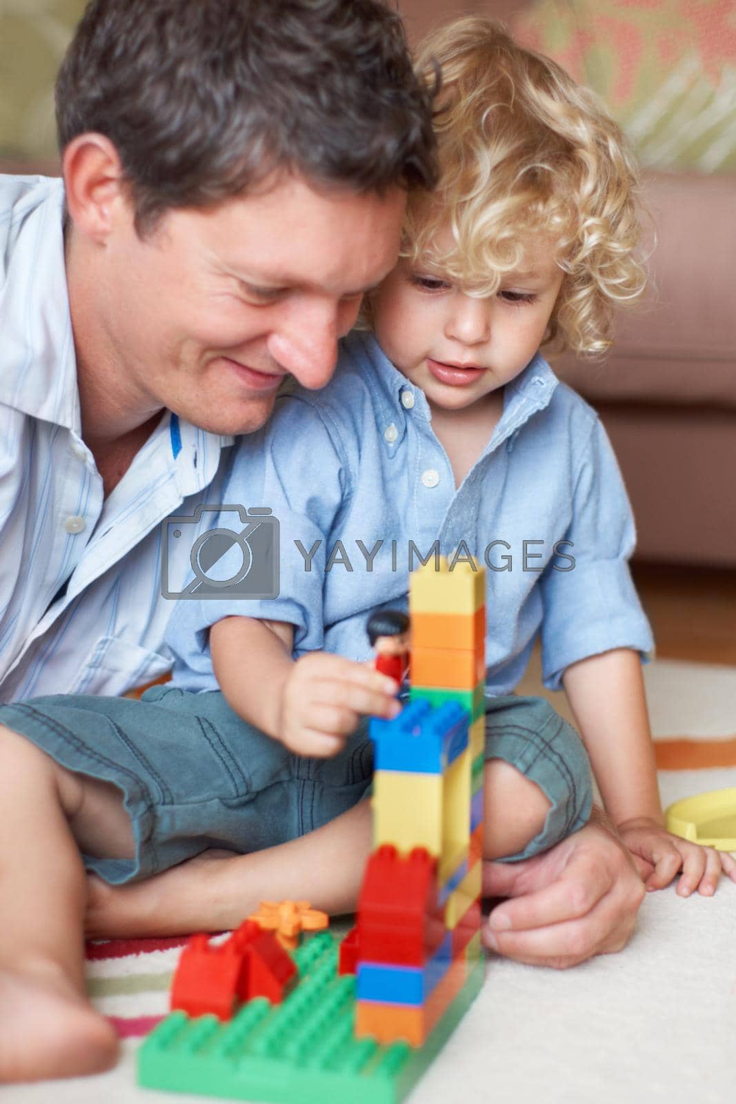 Royalty free image of Hes a brilliant builder just like his dad. A father watching his toddler son playing with building blocks. by YuriArcurs