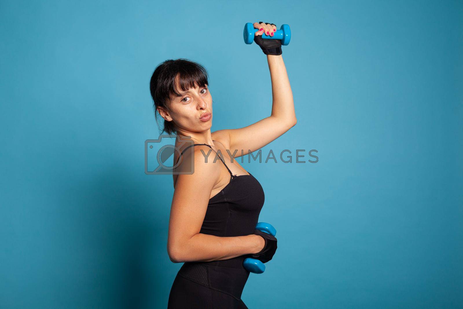 Royalty free image of Portrait of smiling active trainer showing arm muscles by DCStudio