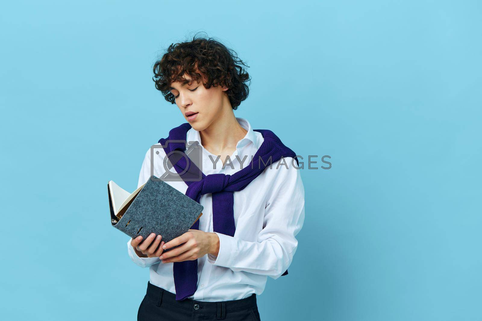 curly guy education with notepad hand gesture blue background. High quality photo