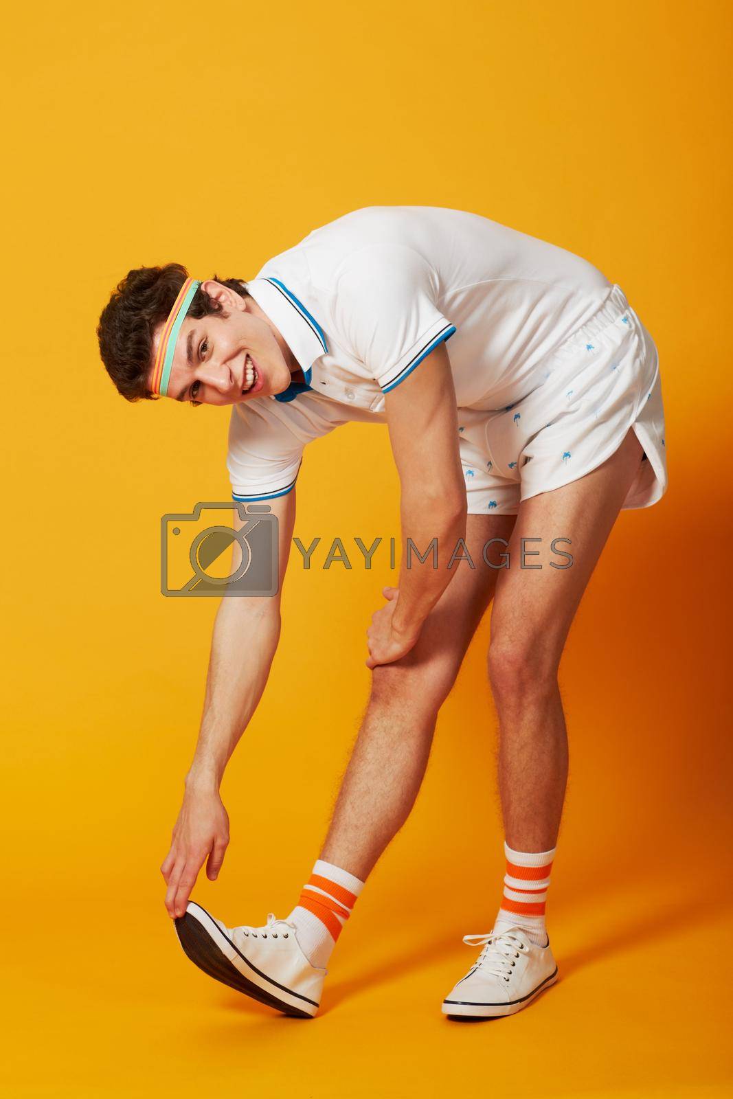 Royalty free image of Stretch it out. A male stretching out his calf muscle in retro sports gear. by YuriArcurs