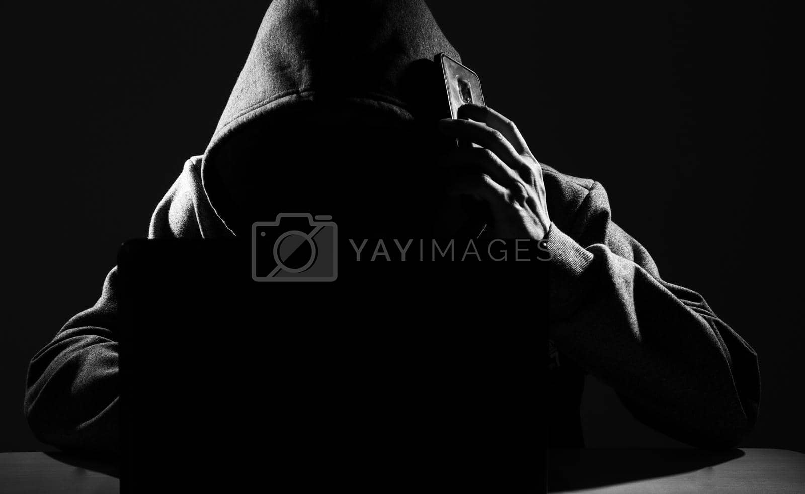 Royalty free image of Hacker Using Smartphone. Men in black clothes with hidden face. by tehcheesiong