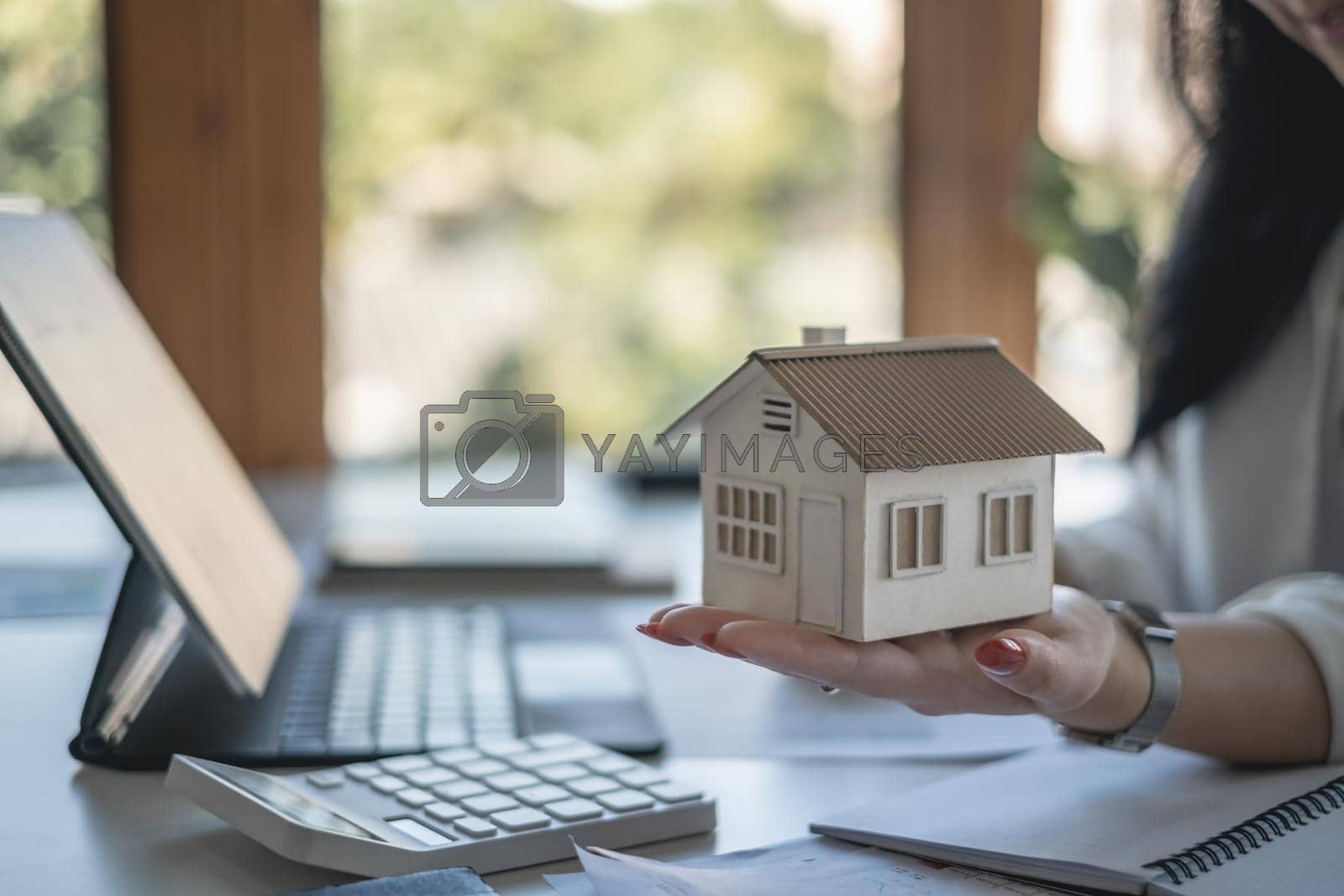 Royalty free image of A woman holding and checking house model .Real Estate House Appraisal And Inspection and Insurance concept. by itchaznong