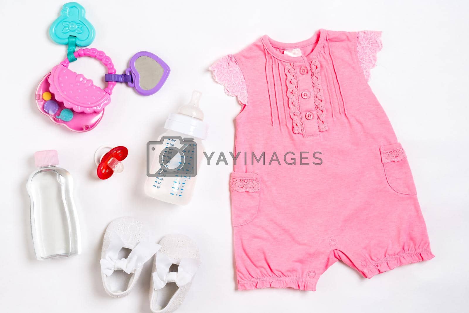 Pink children's costume, bottle and orthodontic pacifier on a white background. Top view. Copy space. Flat lay. Still life