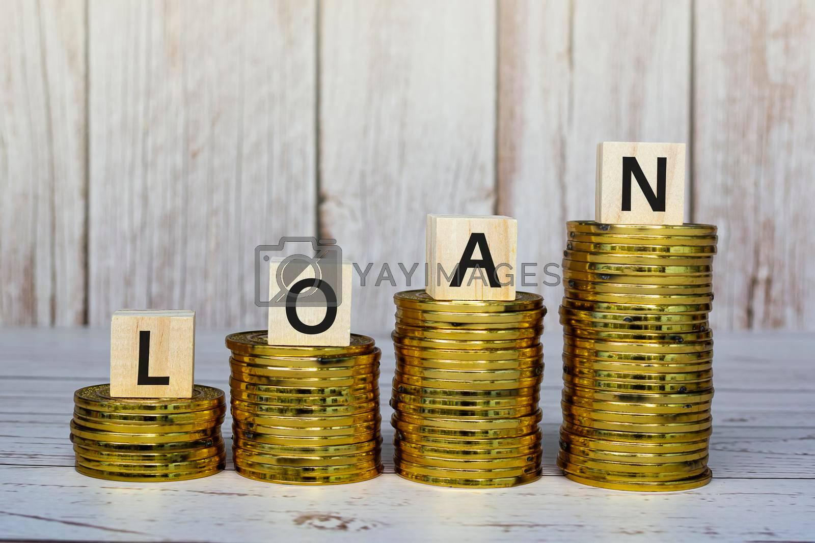 Royalty free image of Loan text on wooden blocks with gold coins on a wooden table. Mortgage concept. by JennMiranda