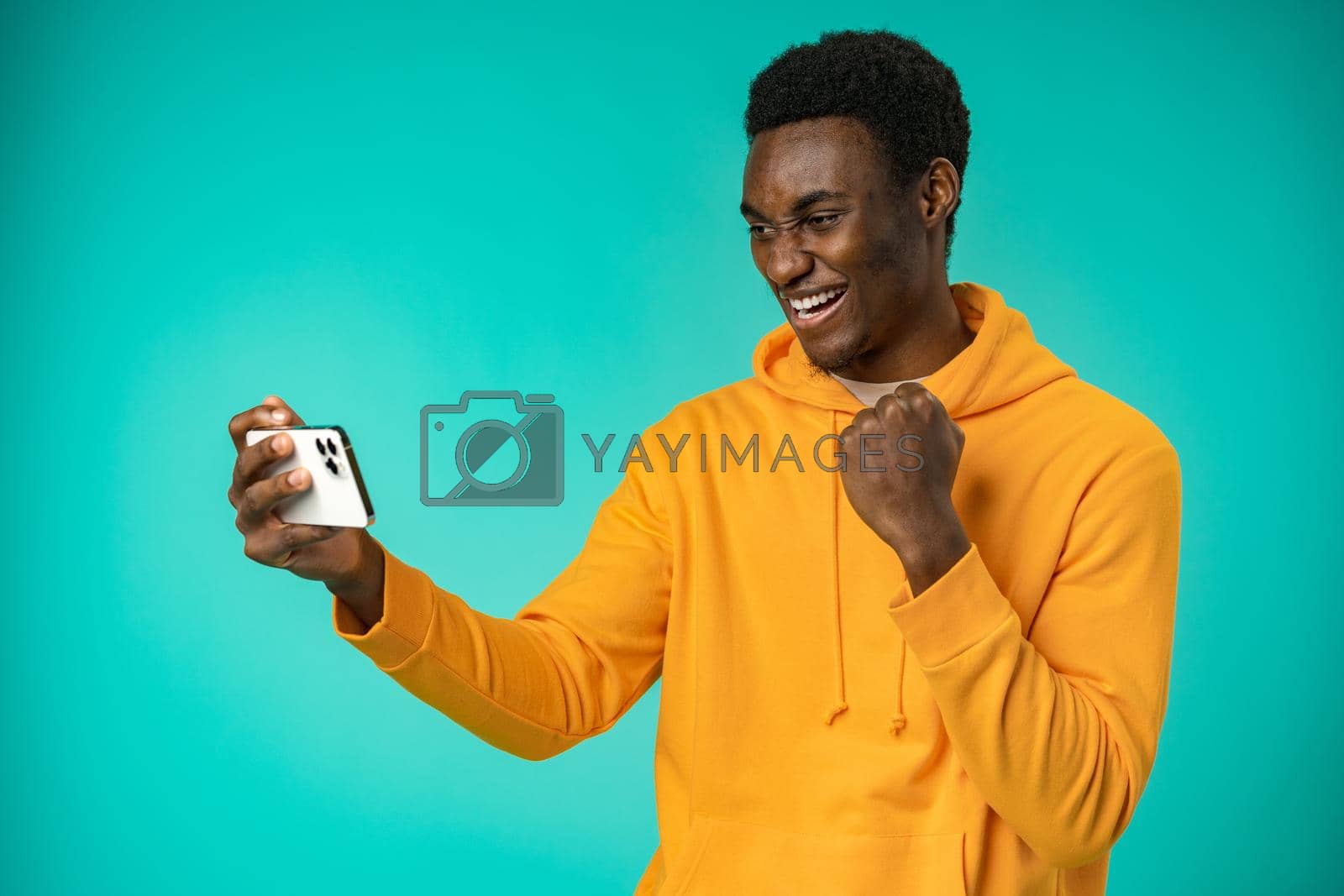 Royalty free image of Excited black man reading good news on cellphone in studio by Fabrikasimf
