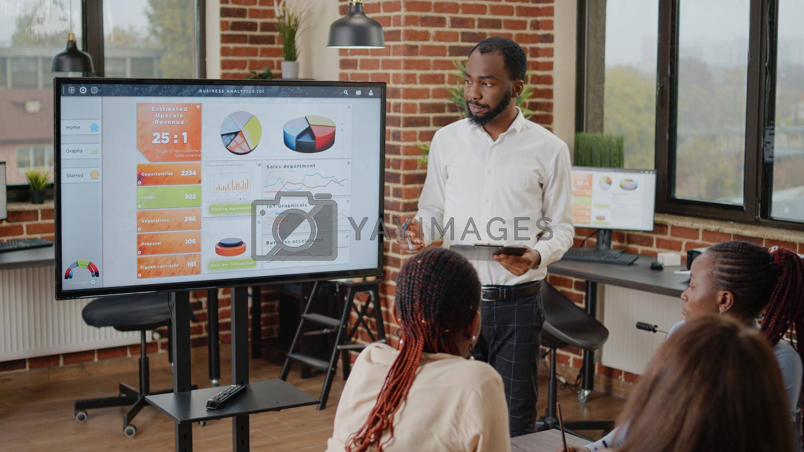 African american man doing financial presentation with charts, talking about business growth to colleagues in startup office. Employee explaining data analysis and project planning.