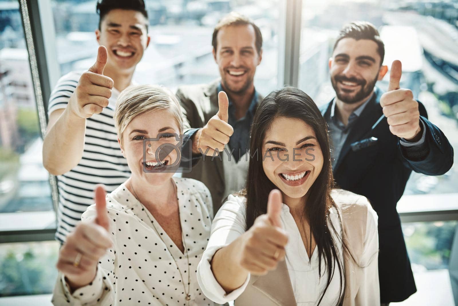 Royalty free image of Their success rate is very high. Portrait of a group of cheerful businesspeople standing together while showing thumbs up to the camera inside of the office. by YuriArcurs