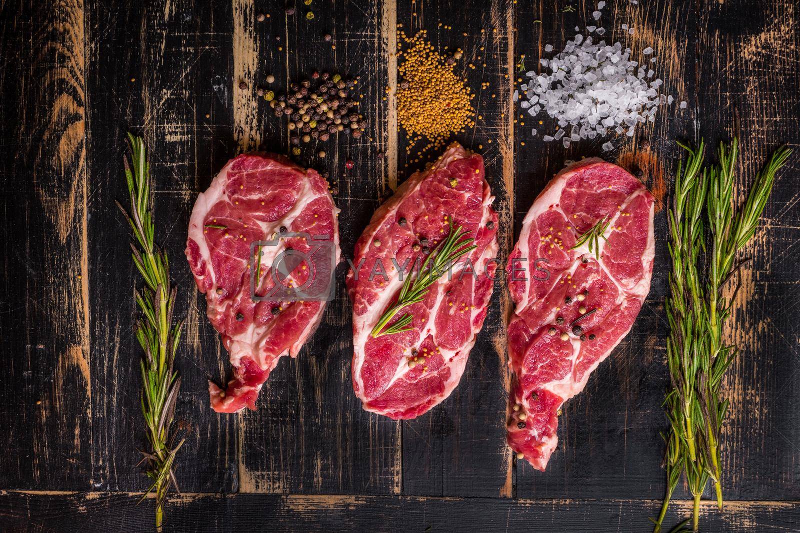 Royalty free image of Raw meat steak on dark wooden background ready to roasting by its_al_dente