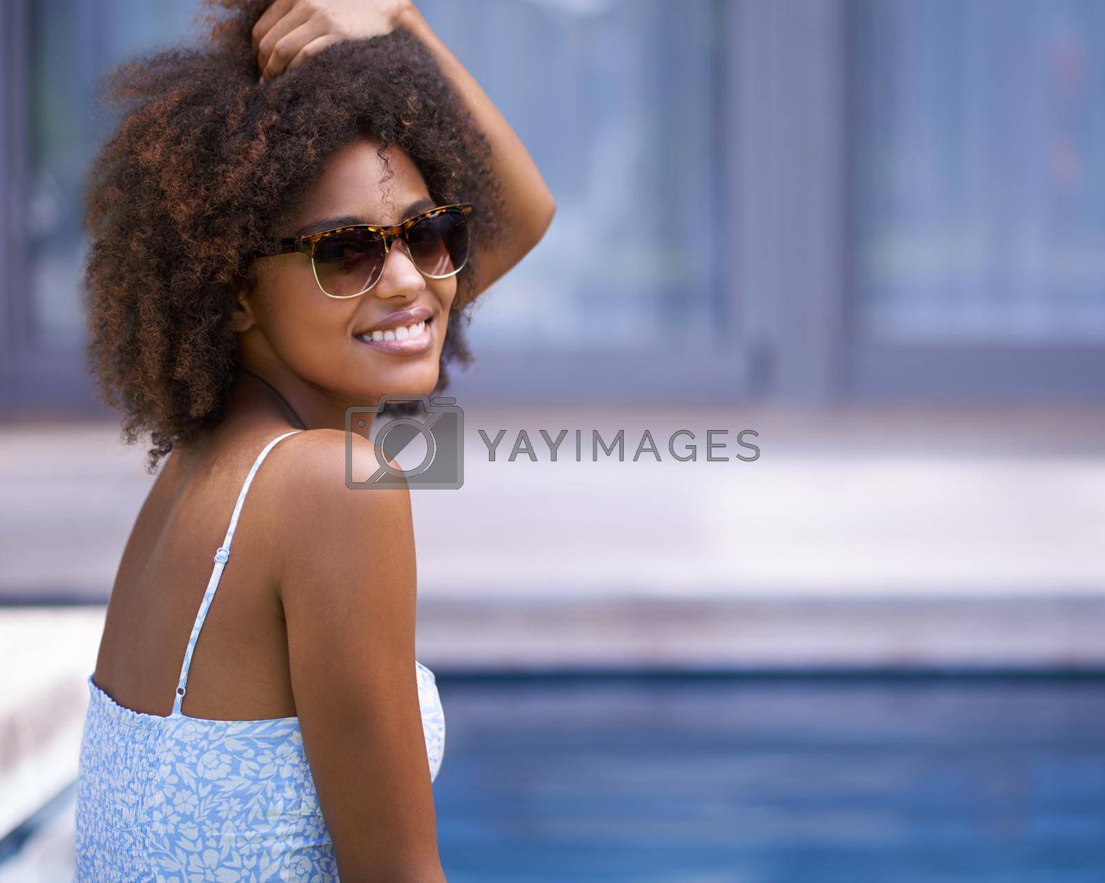 Royalty free image of Now this is what I call relaxation. Shot of an attractive ethnic woman posing in sunglasses by a pool. by YuriArcurs