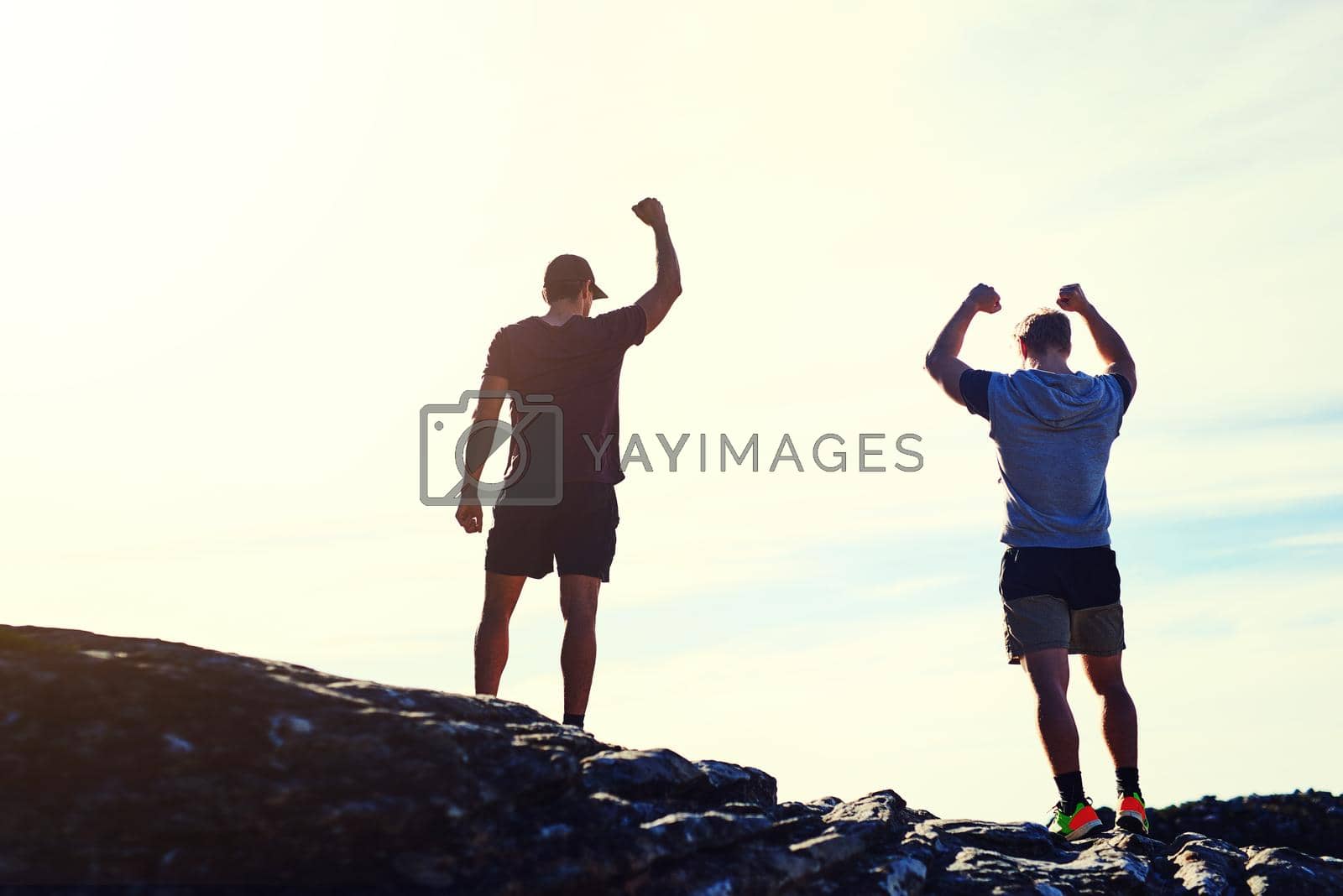Royalty free image of Theres always another mountain to climb. Rearview shot of two unidentifiable young men raising their arms in triumph on a mountaintop. by YuriArcurs