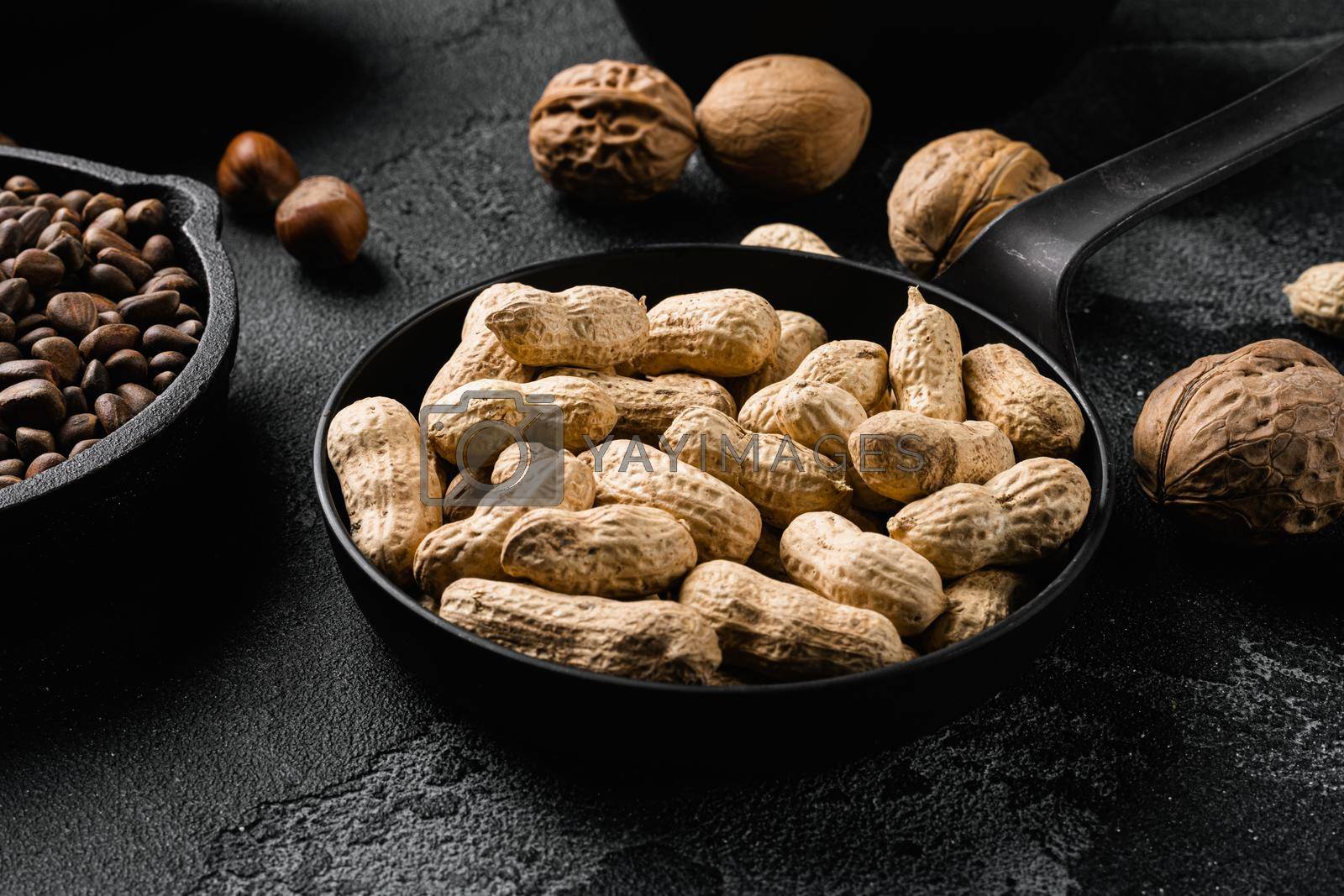 Royalty free image of Dried peanuts. Tasty groundnuts, on black dark stone table background by Ilianesolenyi