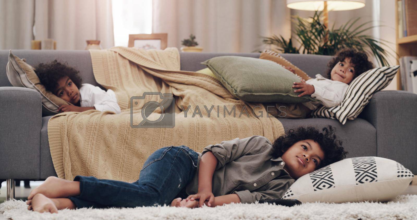 Royalty free image of Might just take a nap. Shot of three adorable little boys laying and watching tv together at home. by YuriArcurs