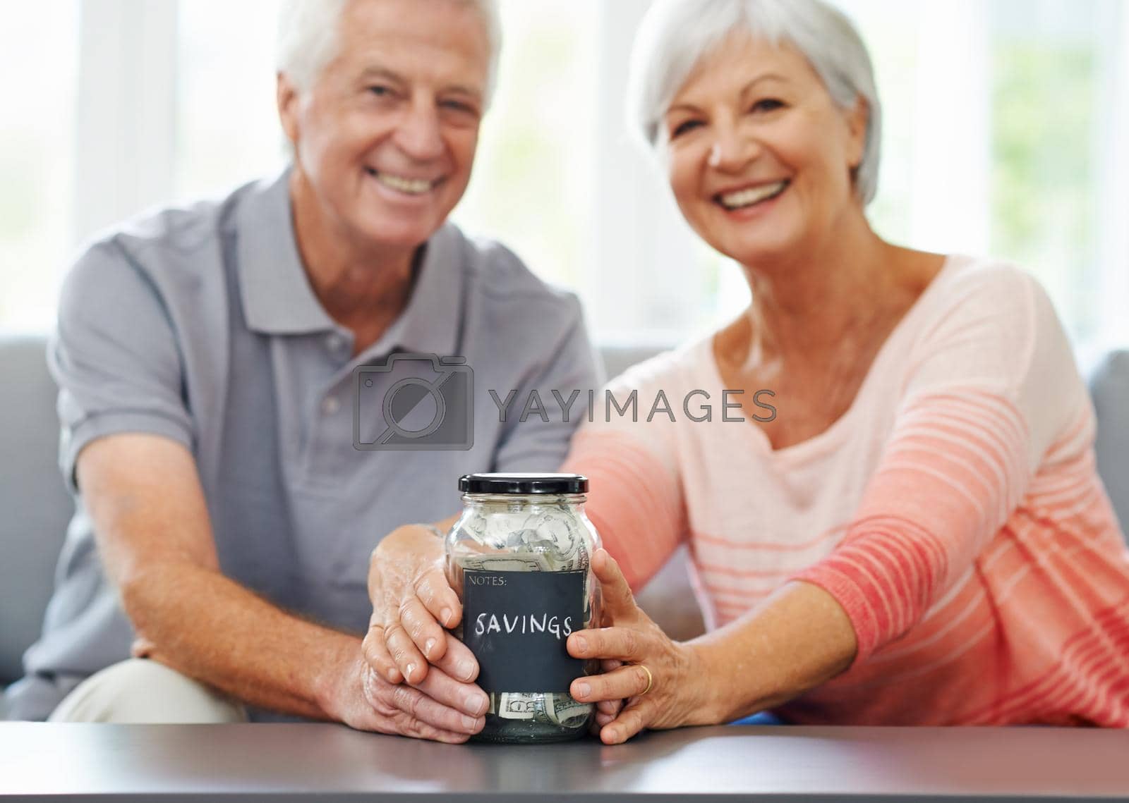 Royalty free image of Look how far weve come. Shot of a senior couple proudly posing with their savings jar. by YuriArcurs