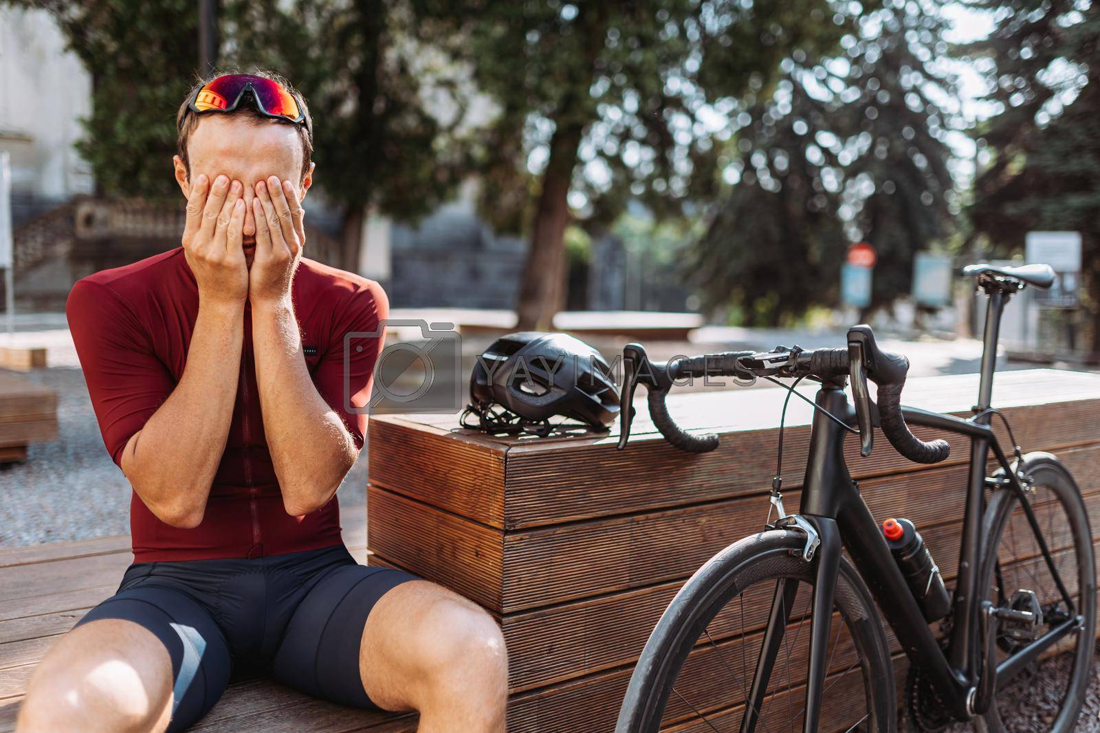 Royalty free image of Tired cyclist massaging face after intense training outdoors by Tymoshchuk