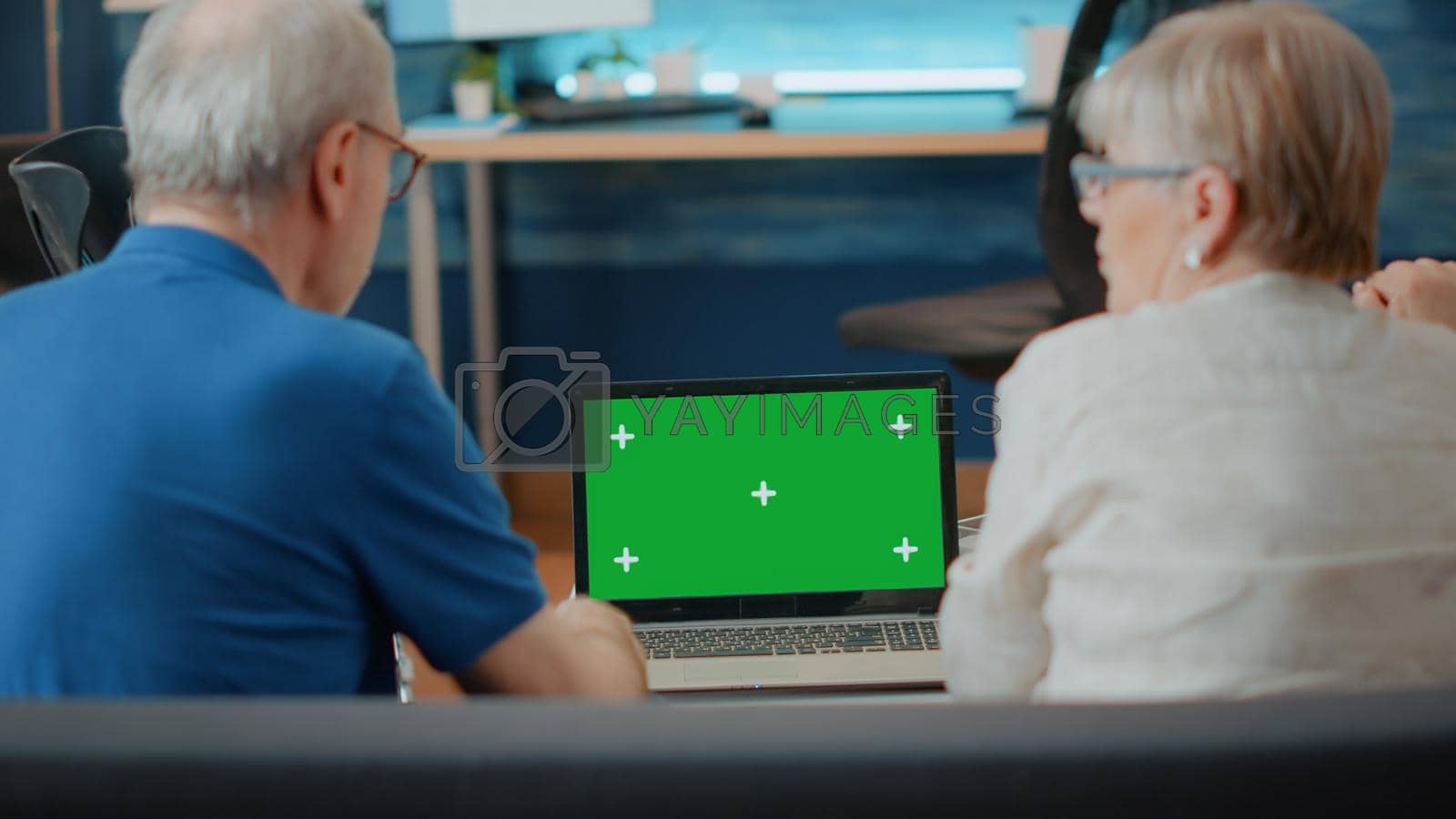 Old people with disability analyzing laptop with green screen. Retired couple looking at copy space template and isolated mock up with blank chroma key on computer background. Modern technology