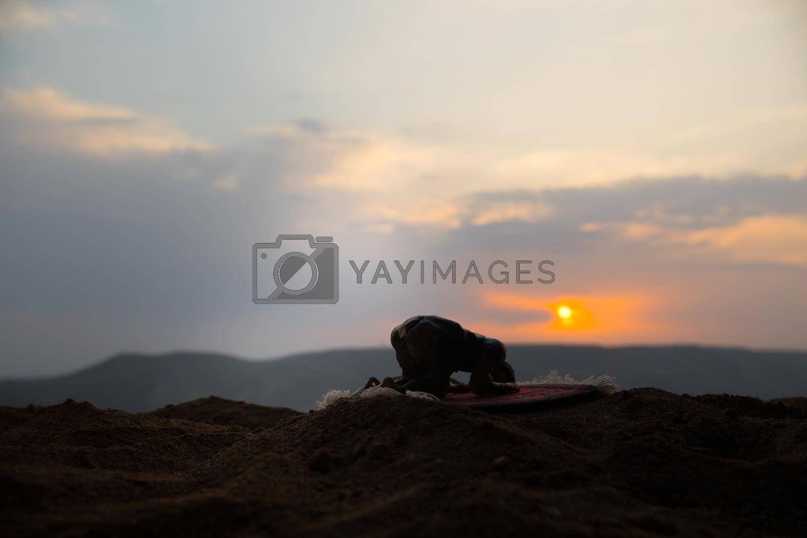 Silhouette of muslim prayer on sunset. Ramadan Kareem background. Praying people. Selective focus