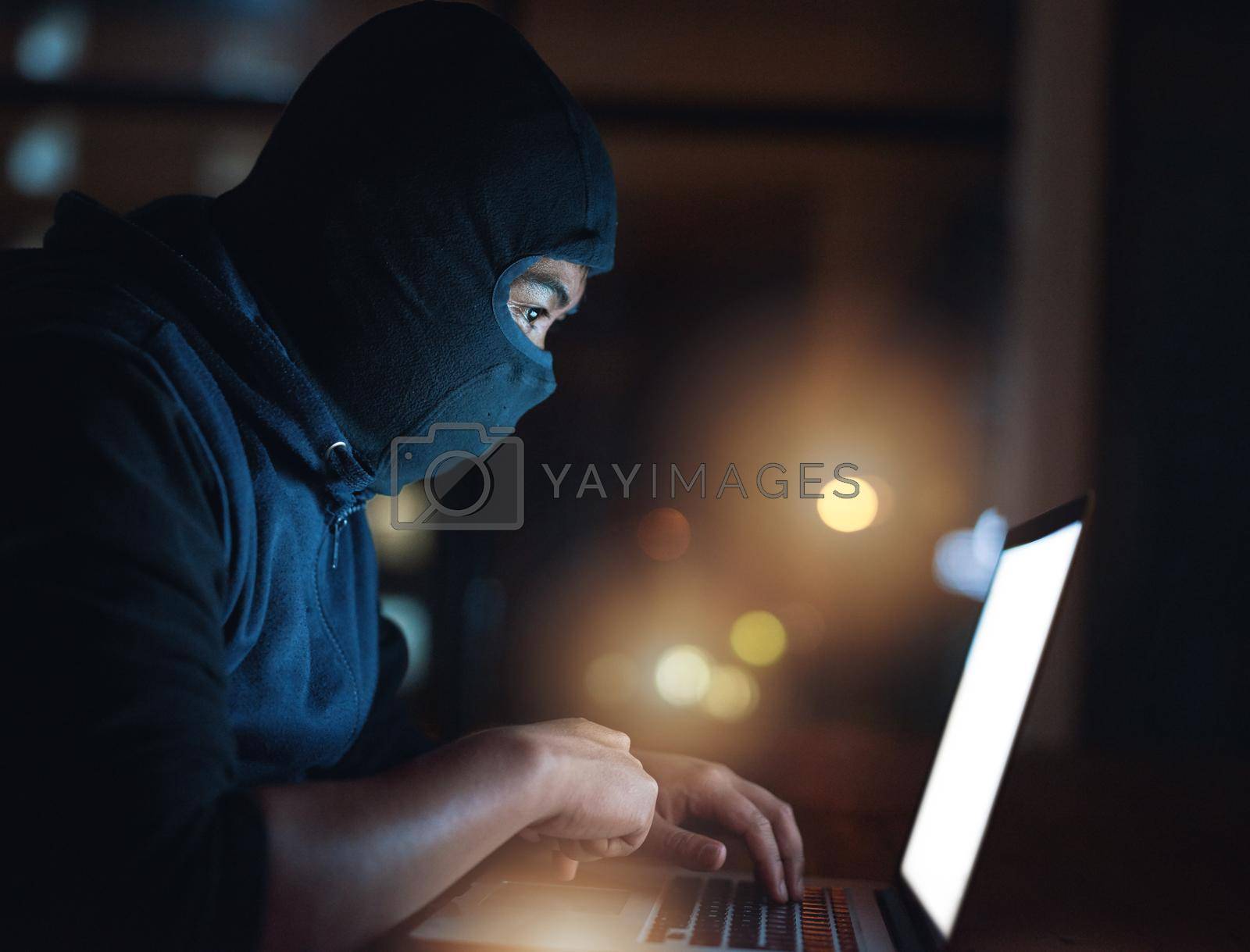 Royalty free image of How secure is your system really. Shot of a hacker using a laptop in the dark. by YuriArcurs