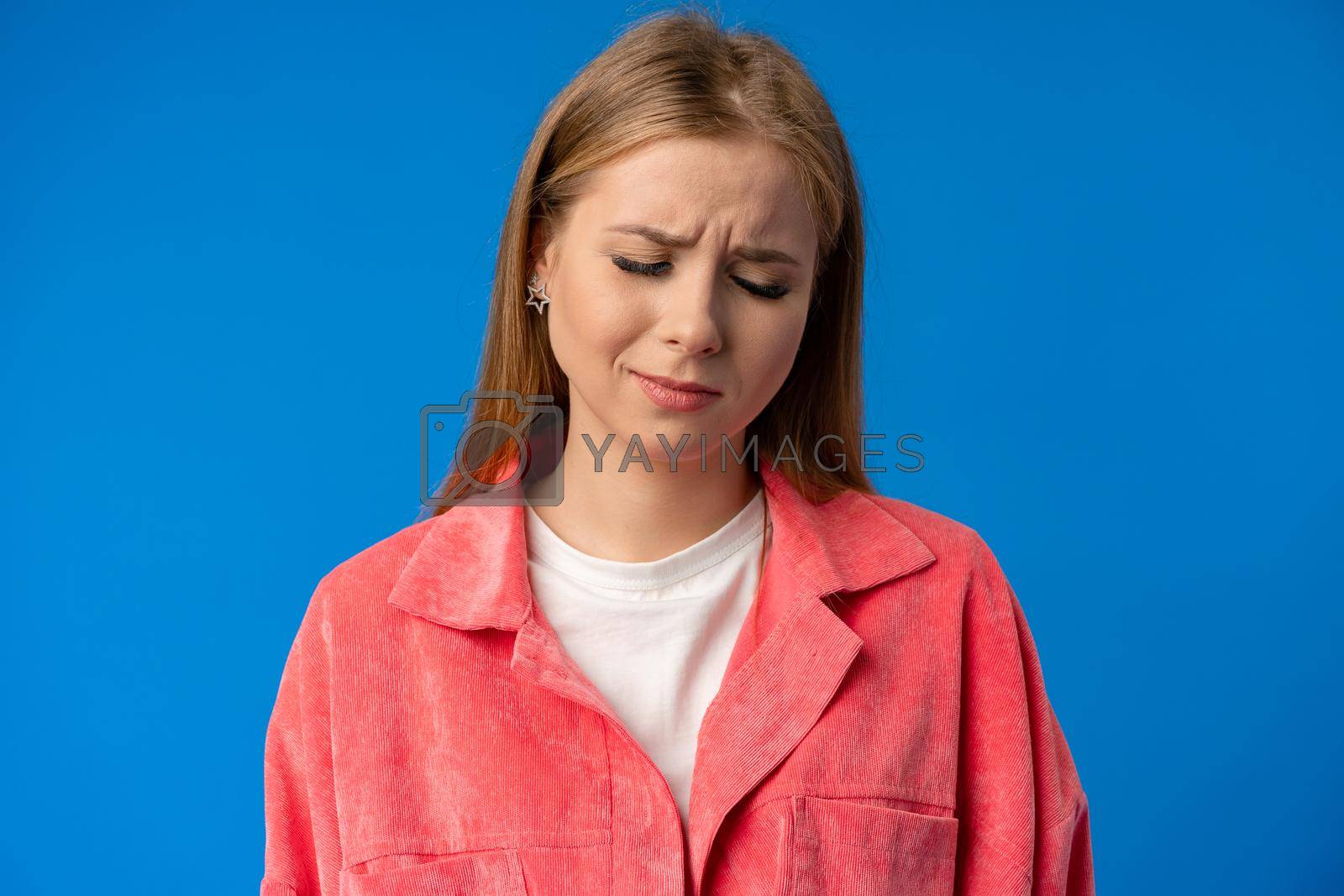 Royalty free image of Negative nervous young woman in trouble over blue background by Fabrikasimf