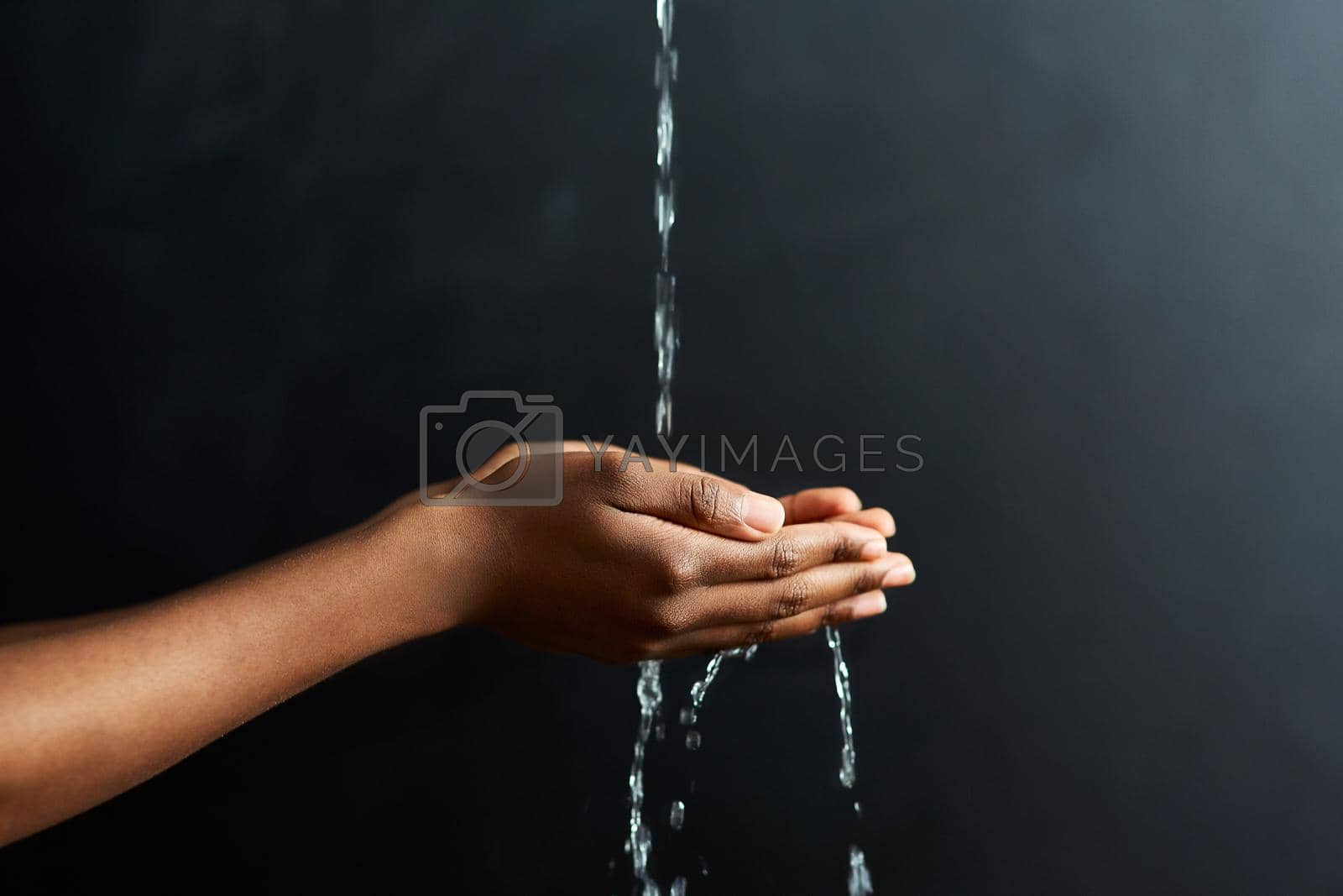 Royalty free image of Purity in the palm of your hands. Cropped shot of hands held out under a stream of water against a grey background. by YuriArcurs