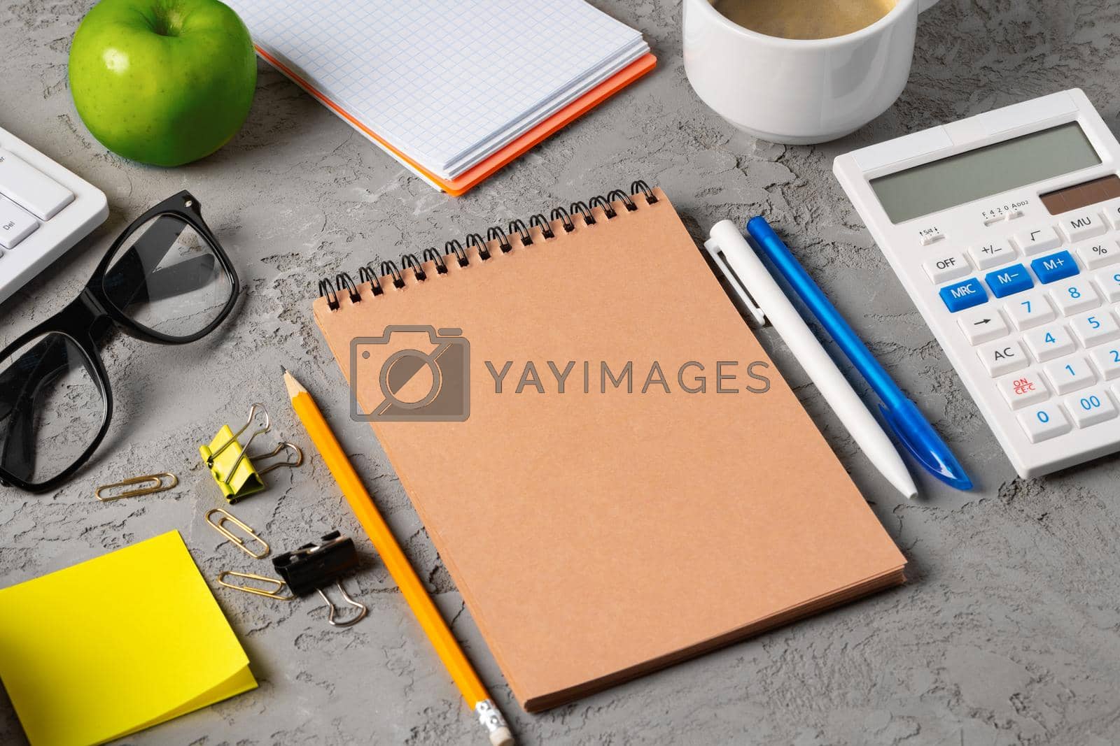 Royalty free image of Office desk with notepad, glasses and supplies by Fabrikasimf