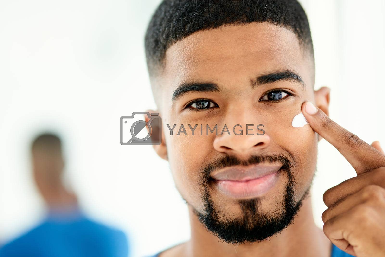 Royalty free image of For smooth and supple skin a good moisturiser is key. Shot of a happy young man applying moisturizer in his bathroom. by YuriArcurs