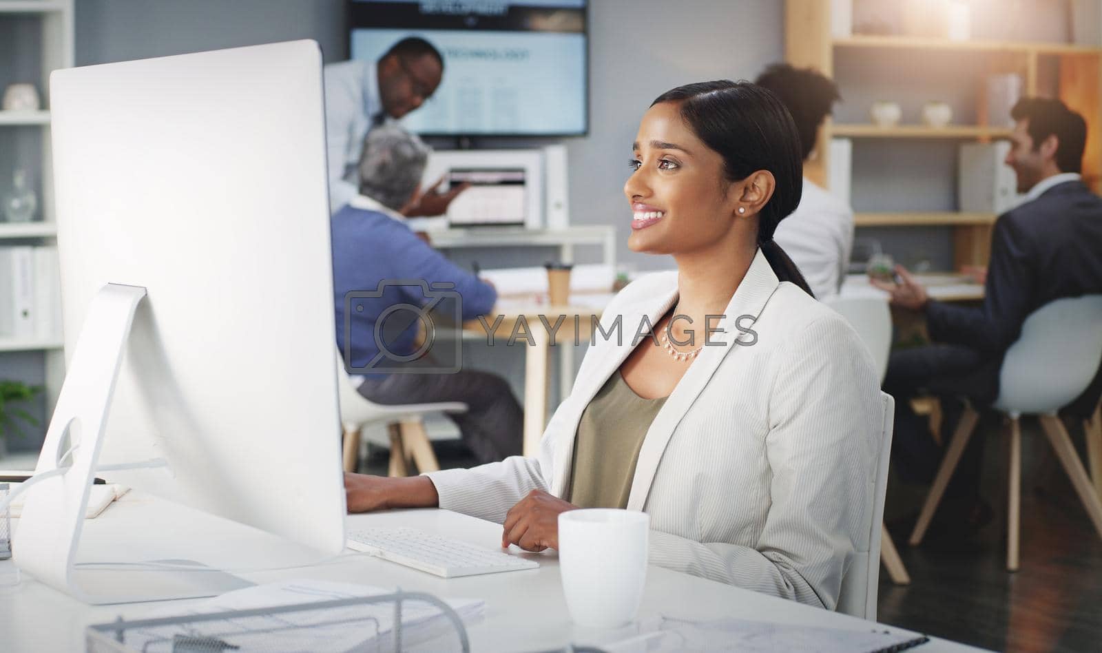 Royalty free image of Positivity improves productivity. Shot of a young businesswoman using a computer at her work desk. by YuriArcurs