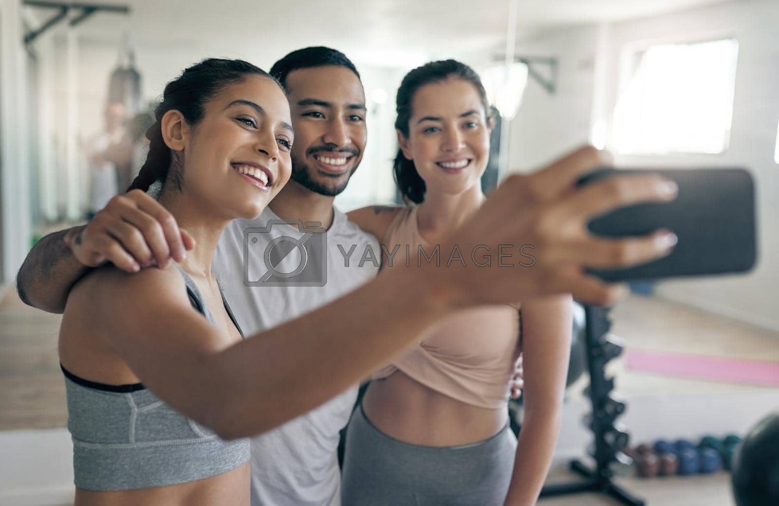 Shot of three young athletes taking a selfie while standing together in the gym.