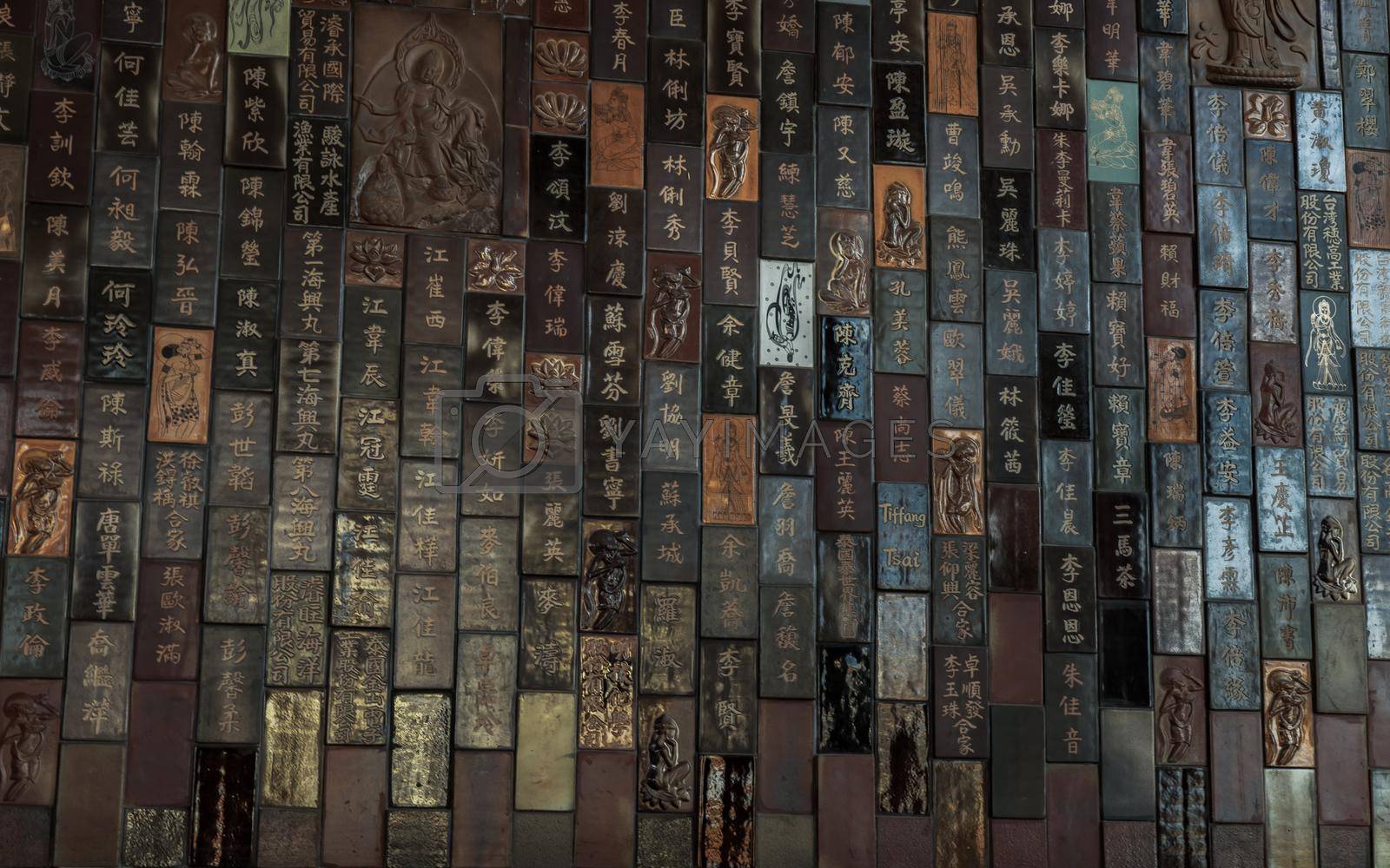 Bangkok, Thailand - Feb 19, 2022 : Chinese lettering teachings and Carved buddha images into a slab of colored tiles on temple wall of Fo Guang San Temple. Focus and blur.