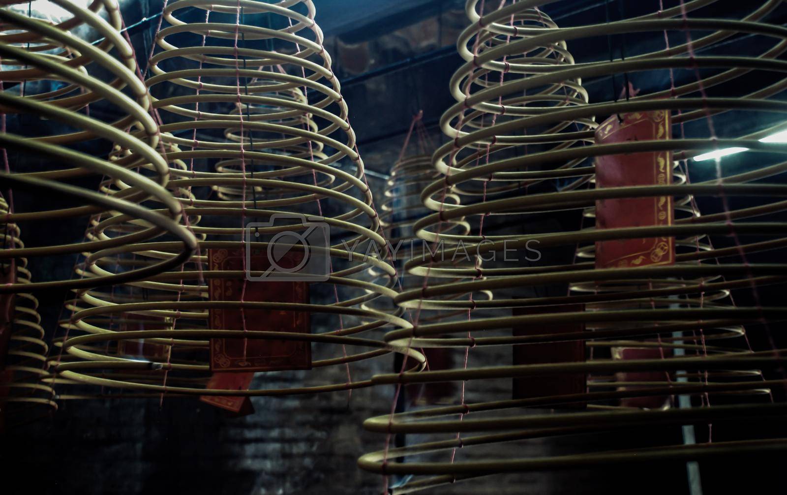 Multiple large yellow incense coils hanging in stacks from the Ceiling in a Chinese shrine. Large Bell Shaped Spiral Incense Coils, Focus and blur.
