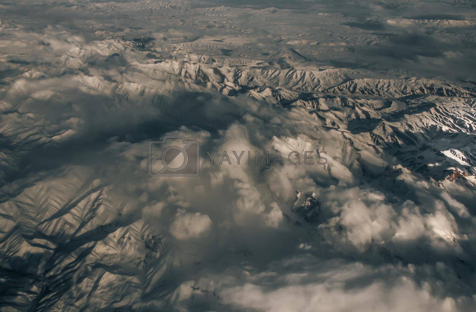 Aerial view from the plane of hills snow and mountains landscape with shadows of sunlight and clouds covered beautifully. Above the clouds, Snow capped mountain, No focus, specifically.