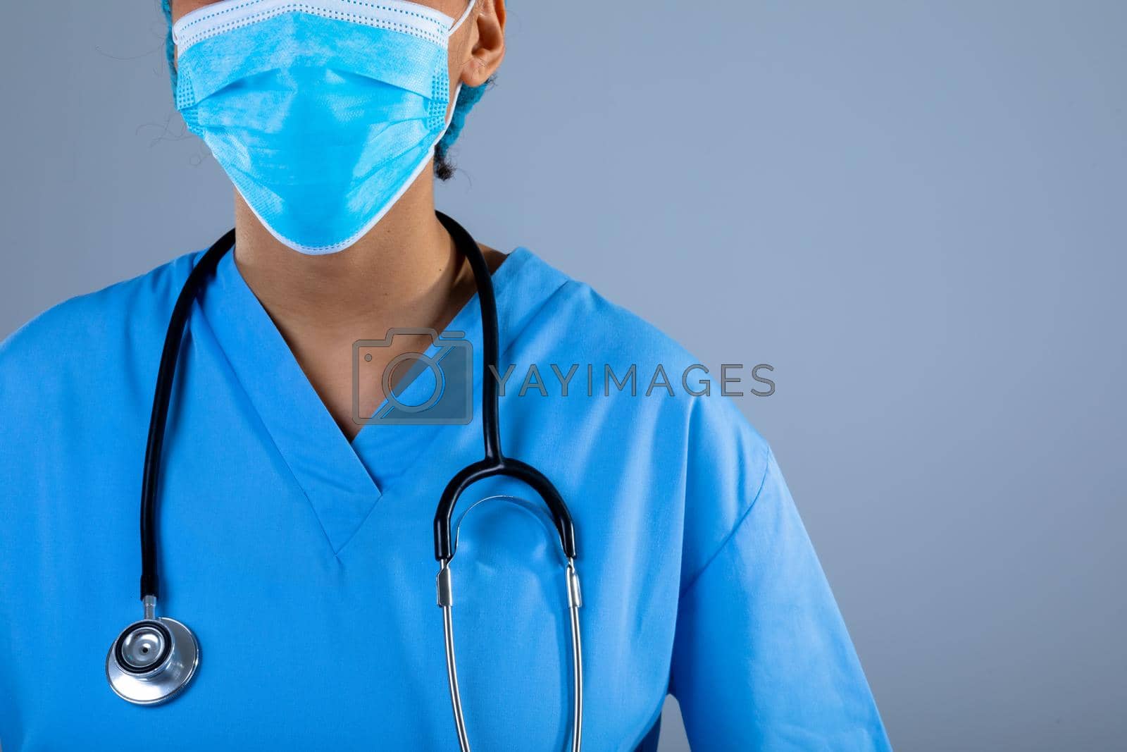 Royalty free image of Mid section of female surgeon wearing face mask against grey background by Wavebreakmedia