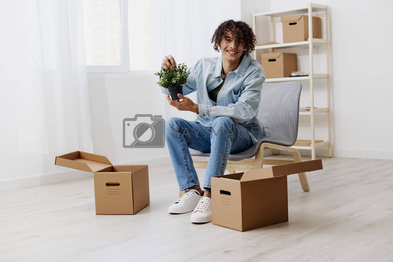 guy with curly hair cardboard boxes in the room unpacking Lifestyle. High quality photo