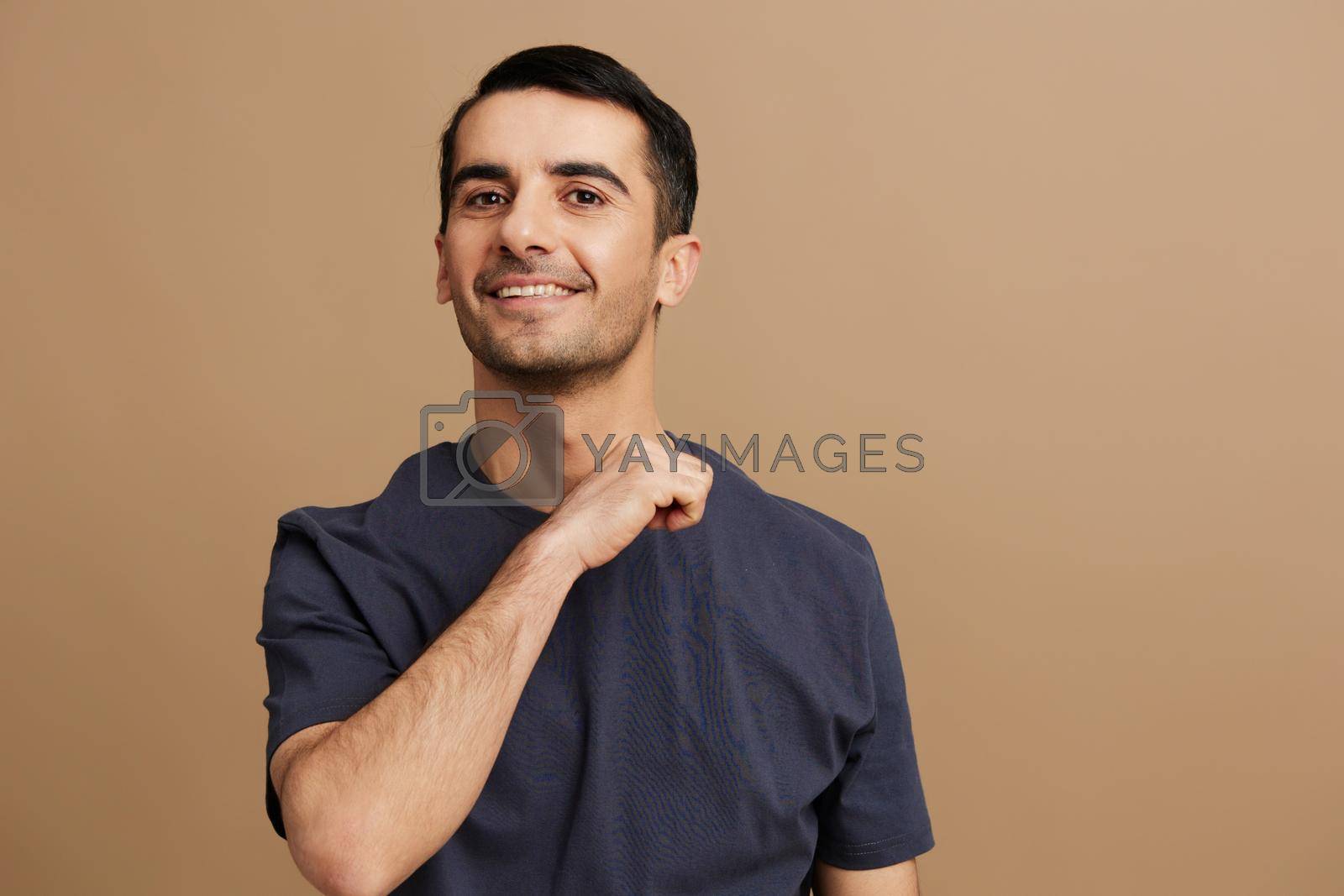Cheerful man hand gesture gray t-shirt fun lifestyle beige background. High quality photo