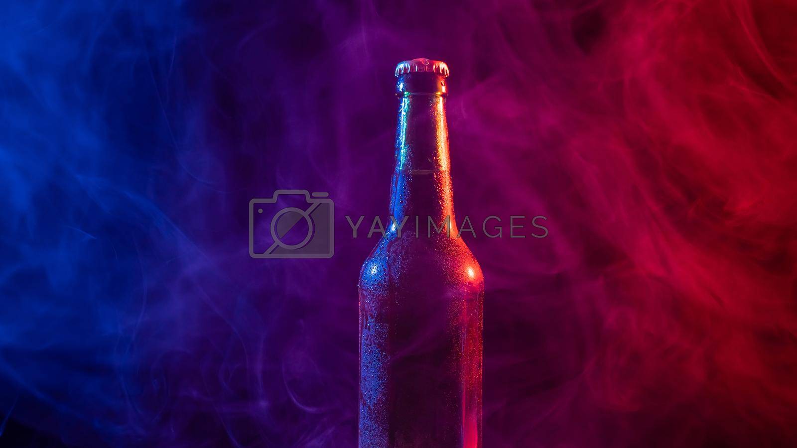 Royalty free image of Glass bottle of beer in blue pink mist by mrwed54