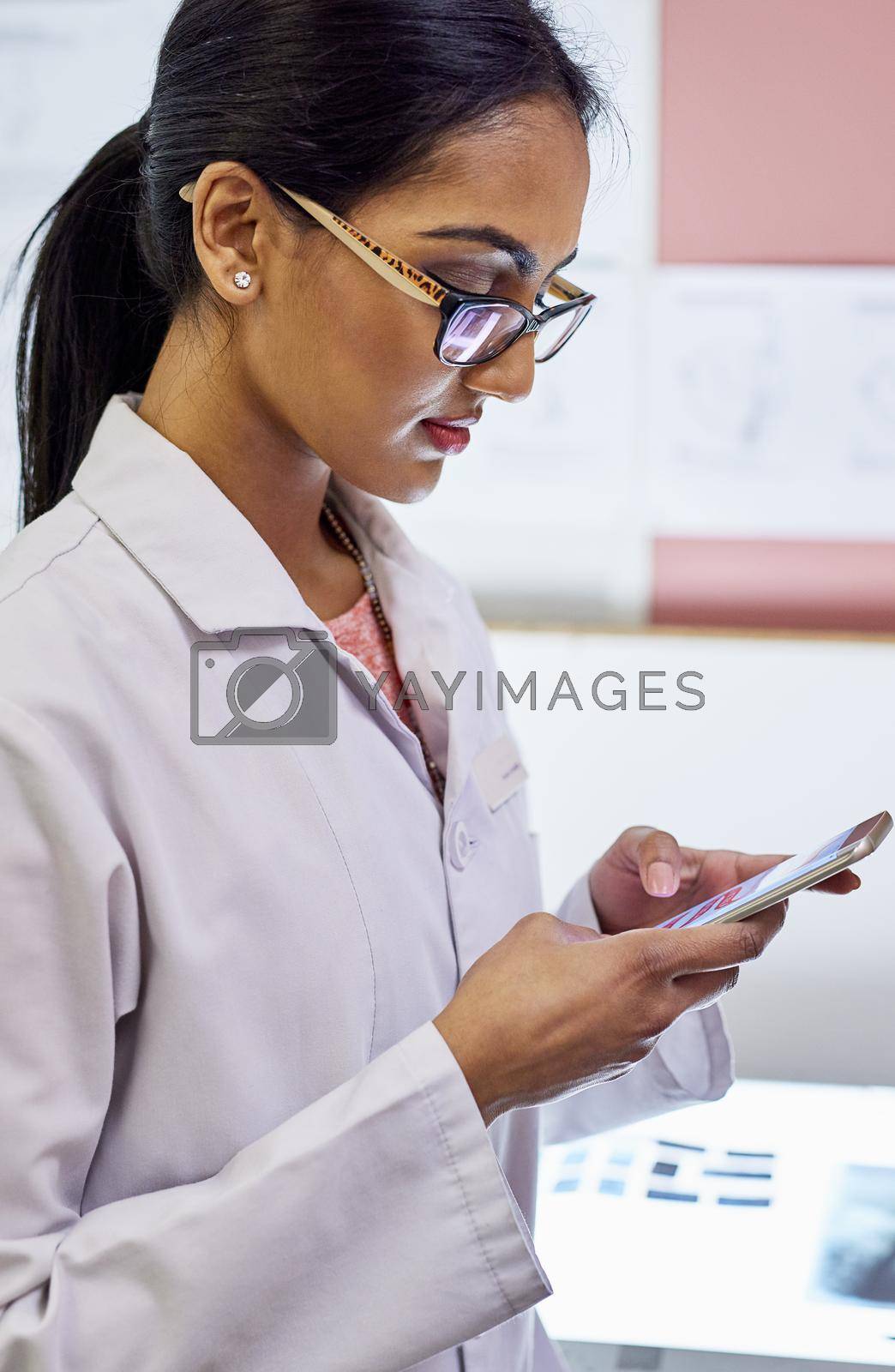 Cropped shot of a young female dentist texting on her cellphone in her office.