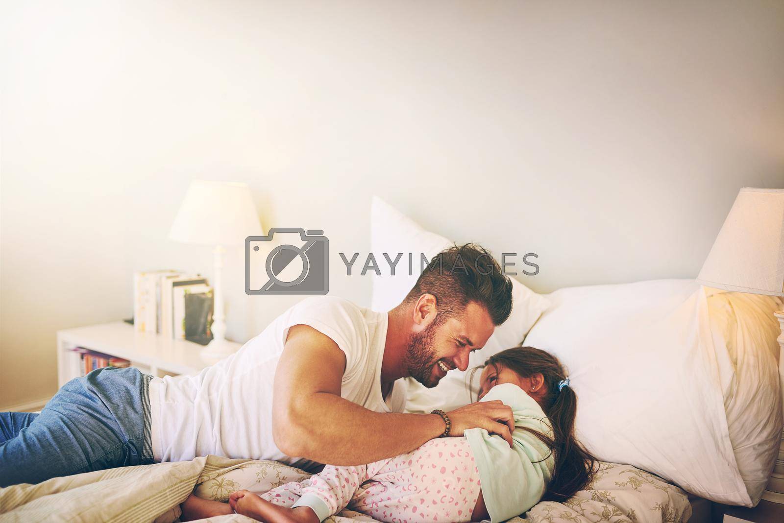 Shot of a cheerful father and daughter having a tickle fight on the bed at home.