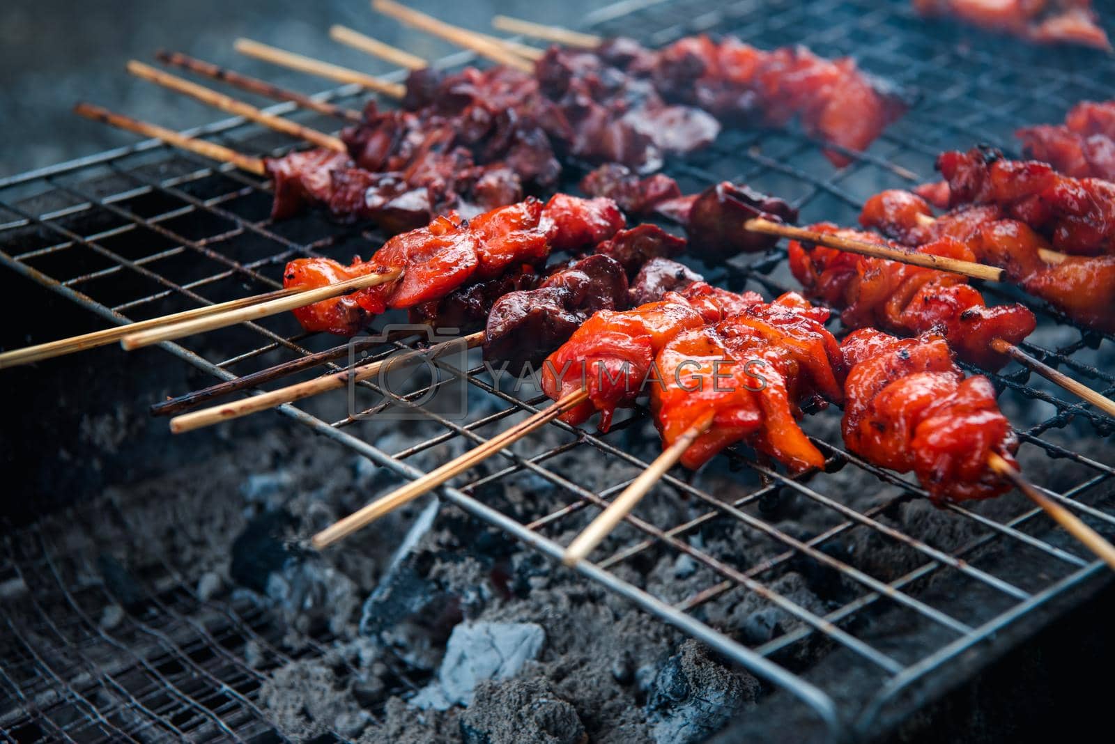 Grilled chicken sauce is a Thai barbeque food by chicken and sauce cooking on charcoal with flames at Thai street food market